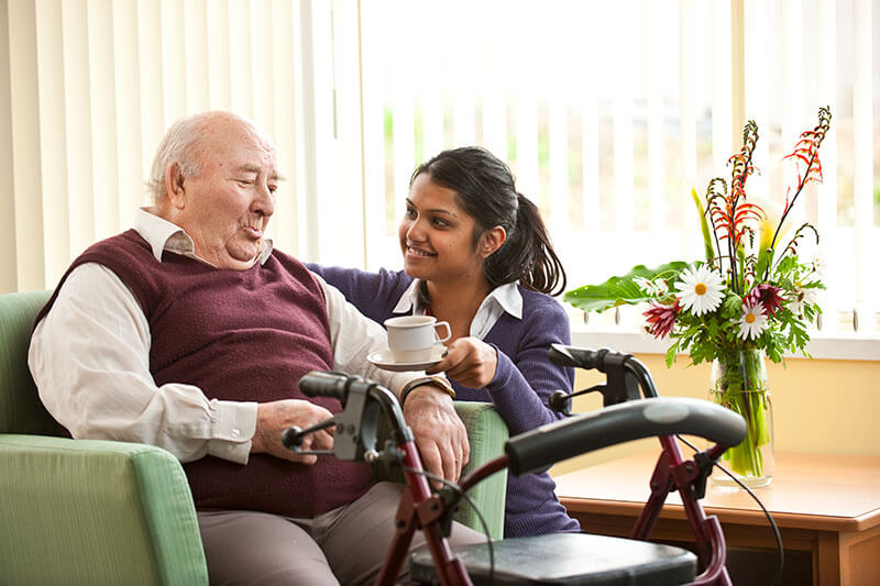 Carer giving a man a cup of tea at Kalyna Care