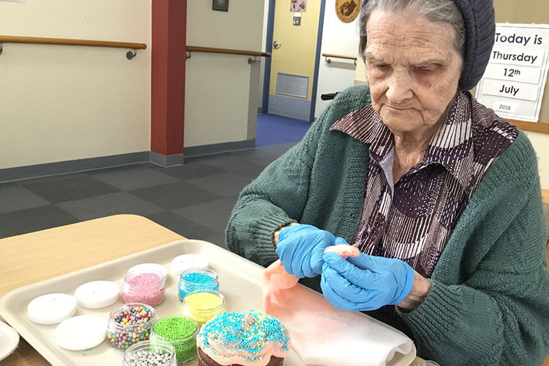 Lady decorating a cupcake at Kalyna Care
